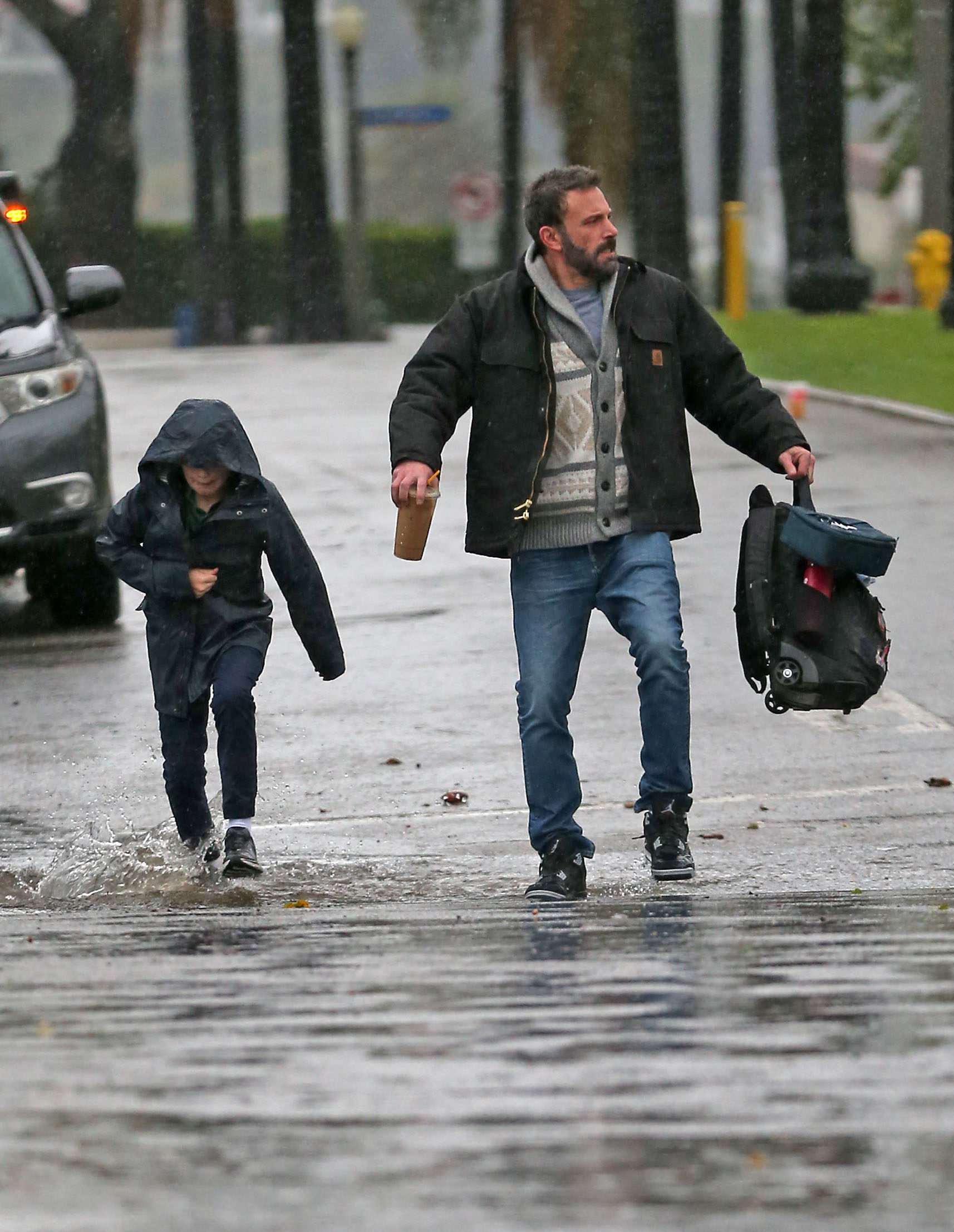 Ben Affleck and son Samuel, 11, dodge puddles as they brave the rainy weather in LA